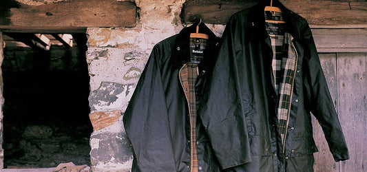 Two Barbour Beaufort Wax Jackets Handing on Coat Hangers in an Old Barn