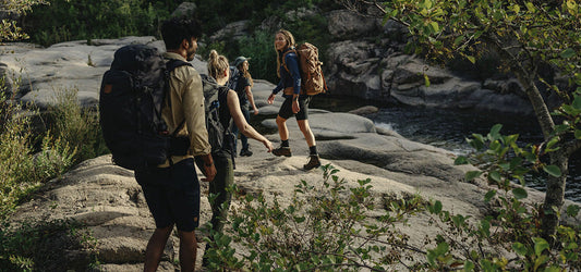 Group of people hiking with backpacks across rocky terrain