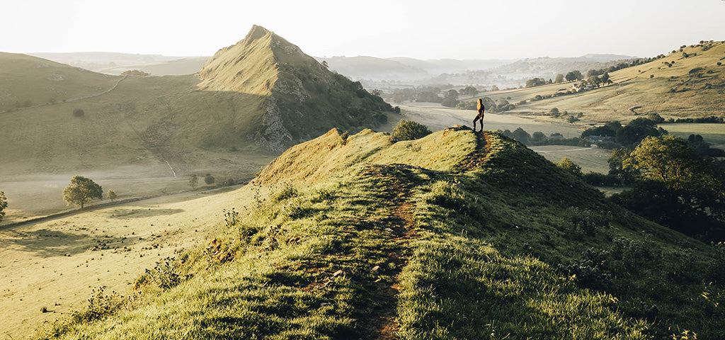 Photographer Brad Matthews captures a lone hiker on a scenic ridge in a verdant landscape. Stunning photography of expansive valleys and rolling hills.