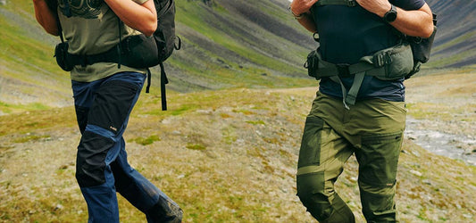 Two men walking through the wilderness wearing Fjallraven trousers