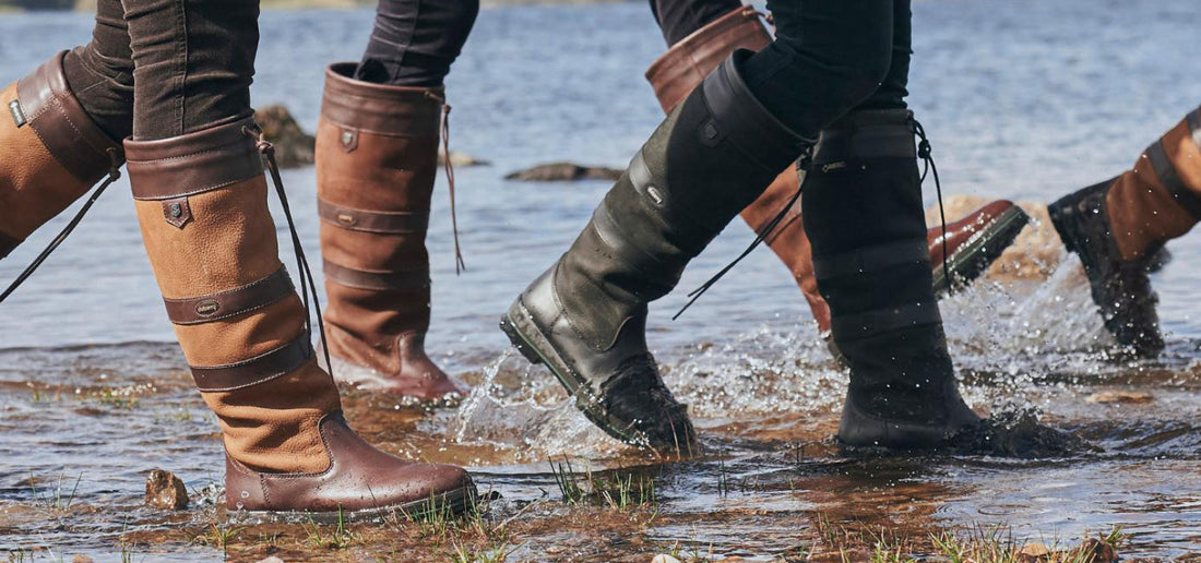 Dubarry leather country boots walking through shallow water on muddy shoreline, waterproof footwear for countryside and field use