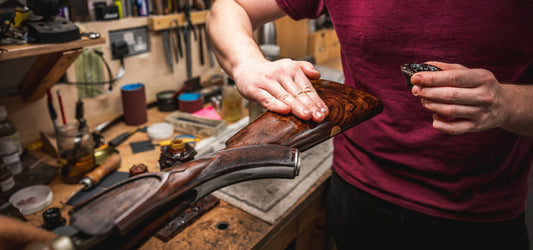 Gunmaker cleaning a shotgun stock by hand at James Purdey & Sons workshop during routine seasonal gun care