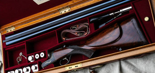 Elegant shotgun in a velvet-lined case, complete with cleaning tools and accessories, showcasing fine craftsmanship and care for shooting equipment.
