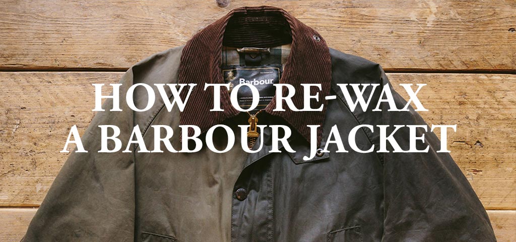 A Barbour waxed jacket displayed on a wooden surface with text "HOW TO RE-WAX A BARBOUR JACKET" overlayed..