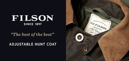 Close-up of Filson Adjustable Hunt Coat showing corduroy collar, front button and internal brand label on waxed cotton jacket