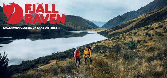Hikers in Fjallraven gear explore a scenic valley by a lake in the Lake District, promoting the Fjallraven Classic UK