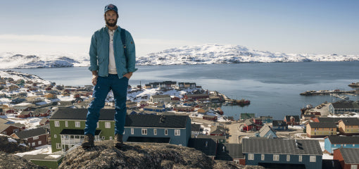 A man wearing a Greenland Jacket standing on a rocky overlook.