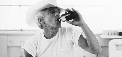 A person in a classic white RRL clothing T-shirt by Ralph Lauren, drinking from a bottle.