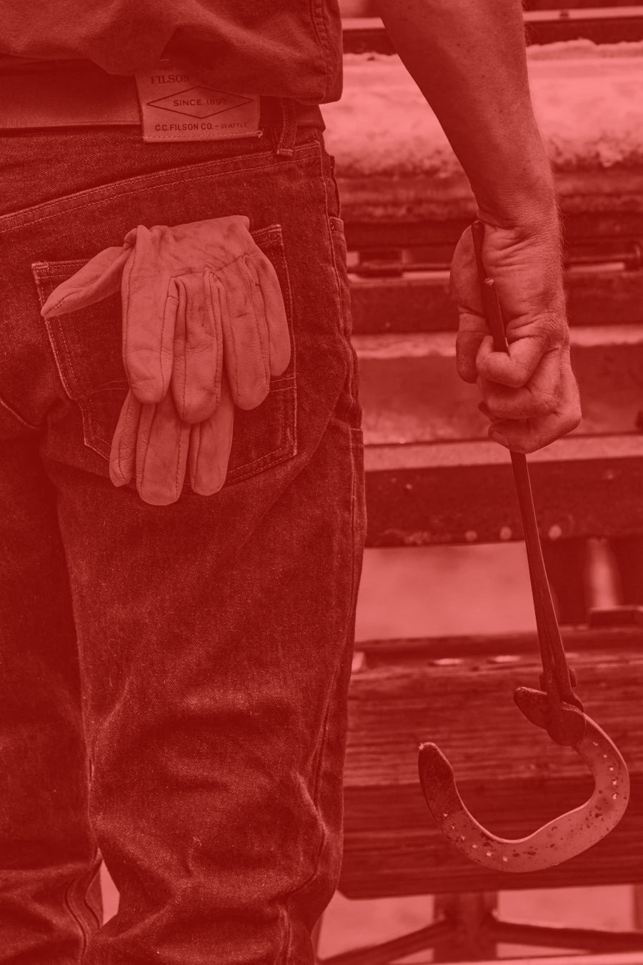 Man wearing Carhartt WIP gloves and holding a tool with a red filter applied